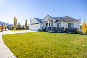Craftsman inspired home featuring stone siding, concrete driveway, a front yard, a garage, and a shingled roof
