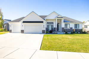 Craftsman house with stone siding, a front yard, concrete driveway, and roof with shingles
