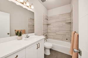 Bathroom with vanity, washtub / shower combination, and dark tile patterned floors