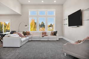 Carpeted living area featuring healthy amount of natural light, recessed lighting, and a towering ceiling