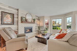 Living area with wooden walls, wood finished floors, a fireplace, and an accent wall