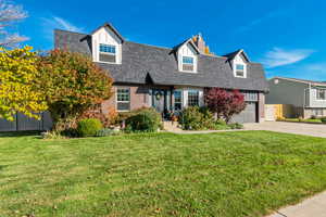 View of front of house featuring a shingled roof, brick siding, driveway, a chimney, and a garage