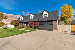 Colonial inspired home with a gate, brick siding, concrete driveway, and a mountain view