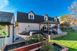 Back of property featuring a deck, a gazebo, a hot tub, and board and batten siding