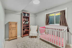 Bedroom with light colored carpet and a crib