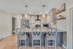 Kitchen with a peninsula, gray cabinets, decorative light fixtures, tasteful backsplash, and recessed lighting