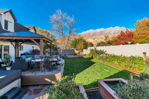 Fenced backyard featuring an outdoor hangout area, a gazebo, a deck with mountain view, a garden, and outdoor dining area