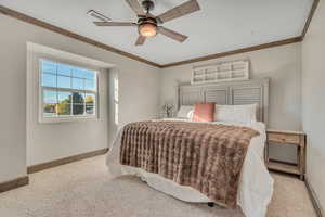 Carpeted bedroom with a ceiling fan and ornamental molding