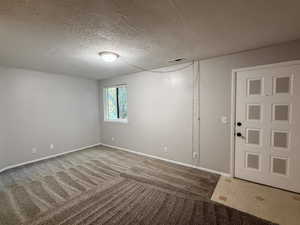 Empty room with a textured ceiling and light colored carpet