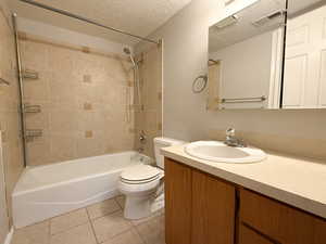 Full bathroom featuring a textured ceiling, light tile patterned flooring, tub / shower combination, and vanity