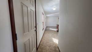 Hall with light tile patterned floors and a textured wall