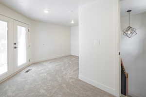 Carpeted empty room featuring french doors and a textured ceiling