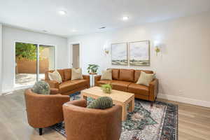 Living area featuring light wood-style floors, a textured ceiling, and recessed lighting