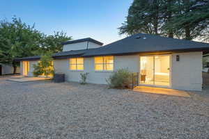 Back of house featuring brick siding and a shingled roof