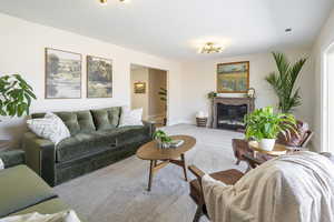 Carpeted living room with a glass covered fireplace and baseboards