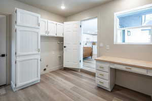 Unfurnished office featuring light wood finished floors, built in desk, recessed lighting, and a textured ceiling