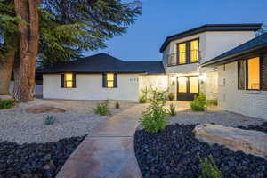 View of front of home with a balcony, stucco siding, french doors, and roof with shingles