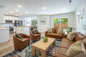 Living area featuring light wood finished floors, plenty of natural light, and recessed lighting