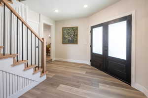 Entryway with light wood-type flooring, stairs, french doors, and recessed lighting