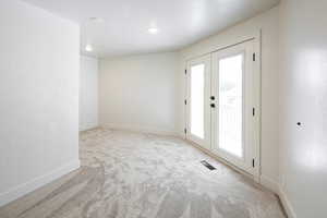 Carpeted empty room featuring a textured ceiling, a textured wall, and french doors