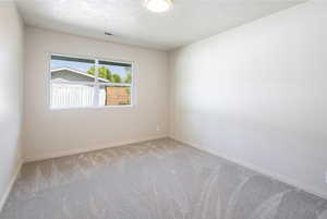 Carpeted empty room featuring baseboards and a textured ceiling