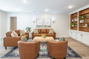 Living room with light wood-style flooring, a textured ceiling, and recessed lighting