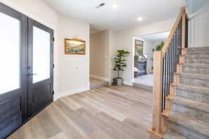 Entrance foyer with light wood-style flooring, recessed lighting, french doors, and stairs