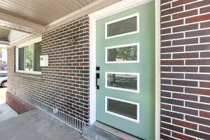 Doorway to property featuring brick siding and a porch