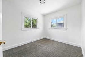 Unfurnished room featuring dark carpet and plenty of natural light