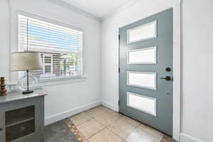 Entryway featuring light tile patterned flooring and crown molding