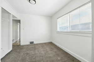 Unfurnished bedroom with dark carpet and baseboards