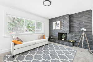Living room with carpet floors, a fireplace with raised hearth, and crown molding