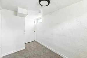 Unfurnished room with a textured ceiling, carpet floors, and a textured wall