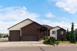 View of front of home with driveway, a garage, and stairs