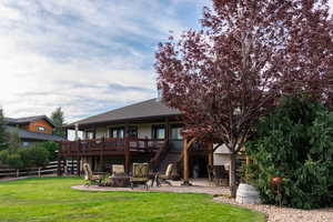 Back of property featuring a patio, a deck, a fire pit, stairs, and a shingled roof