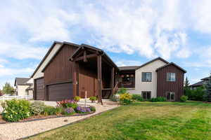View of front of home with stairway, a front lawn, an attached garage, and a wooden deck