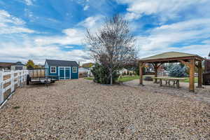 Fenced backyard featuring a patio, a gazebo, and a storage shed