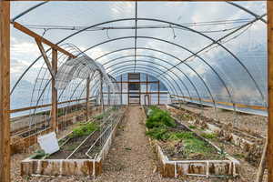 View of community featuring a vegetable garden, a greenhouse, a sunroom, and an outbuilding