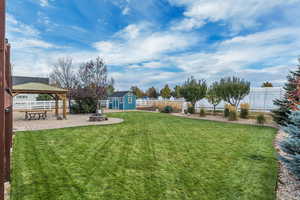Fenced backyard featuring a patio area, a fire pit, a gazebo, and a shed