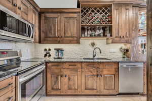 Kitchen with stainless steel appliances, dark stone countertops, backsplash, and open shelves