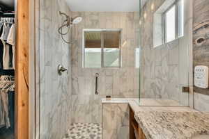 Bathroom featuring a walk in closet and a marble finish shower