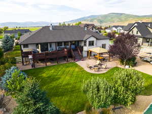 Back of house with a patio area, a fire pit, a deck with mountain view, stairway, and a shingled roof