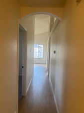 Hallway featuring dark wood-style flooring, arched walkways, and lofted ceiling
