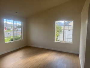 Spare room with healthy amount of natural light, light wood-style flooring, and lofted ceiling