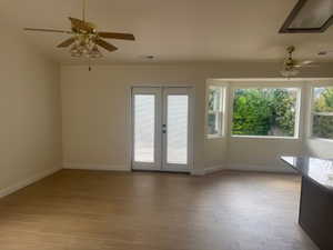 Unfurnished room with ceiling fan, light wood finished floors, and french doors