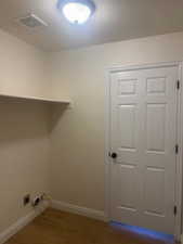 Laundry area featuring baseboards and dark wood finished floors