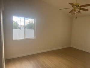 Empty room with light wood-style flooring, vaulted ceiling, and a ceiling fan