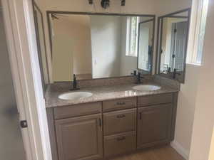 Full bath featuring double vanity and light wood-style flooring