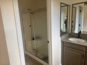 Bathroom featuring vanity, a shower stall, and wood finished floors