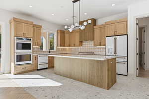 Kitchen with white appliances, tasteful backsplash, recessed lighting, hanging light fixtures, and a kitchen island